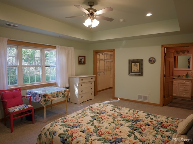 carpeted bedroom featuring a raised ceiling, sink, and ceiling fan