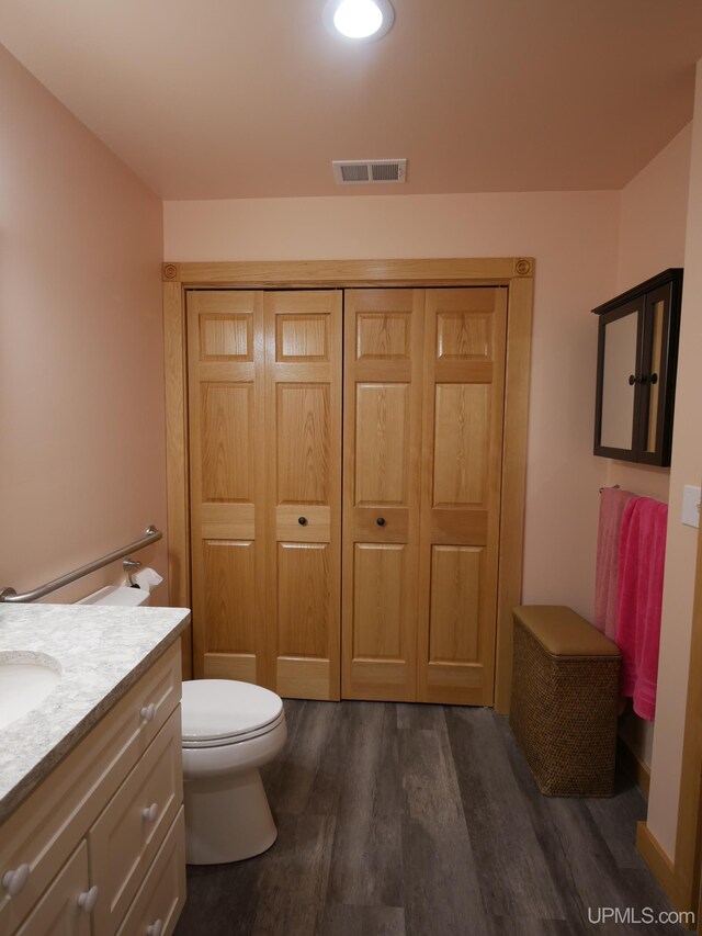 bathroom with toilet, wood finished floors, vanity, and visible vents