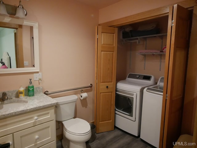 bathroom featuring toilet, wood finished floors, vanity, and washer and clothes dryer