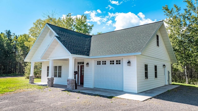 view of front of house featuring driveway, a porch, a shingled roof, and a garage