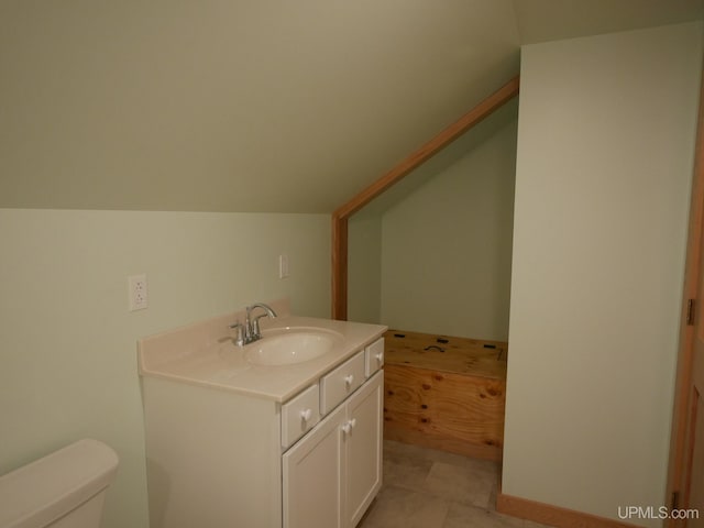 bathroom featuring tile patterned flooring, vaulted ceiling, vanity, and toilet