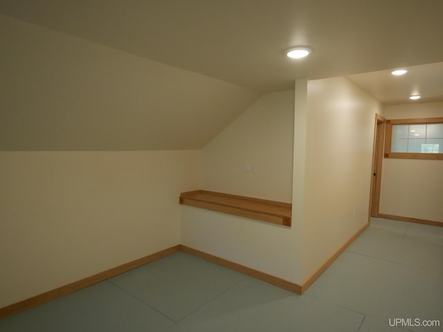 bonus room with light tile patterned flooring and vaulted ceiling