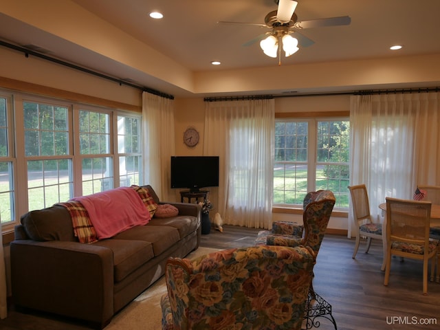 living room with dark wood-type flooring, ceiling fan, and plenty of natural light