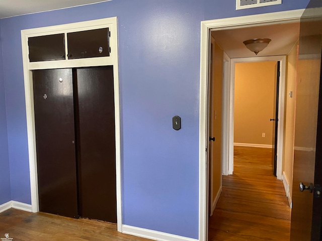 corridor with hardwood / wood-style flooring