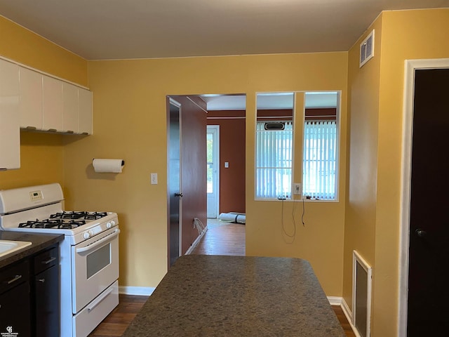 kitchen with white cabinetry, dark hardwood / wood-style floors, and white range with gas stovetop