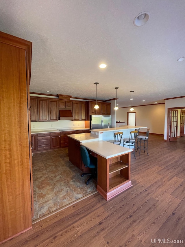 kitchen with stainless steel fridge, a kitchen bar, dark hardwood / wood-style floors, and a large island