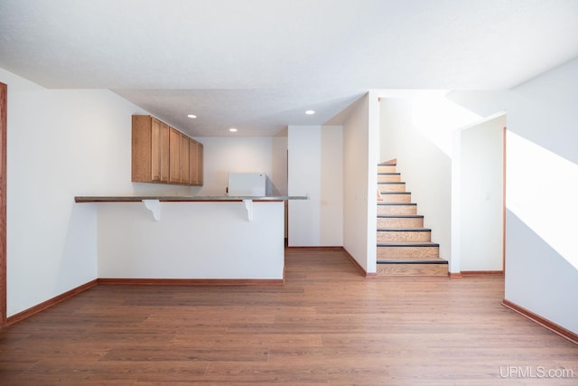 23 Chipman Dr, Ishpeming, MI 49849 - kitchen featuring light wood-type flooring, a peninsula, recessed lighting, a breakfast bar area, and baseboards