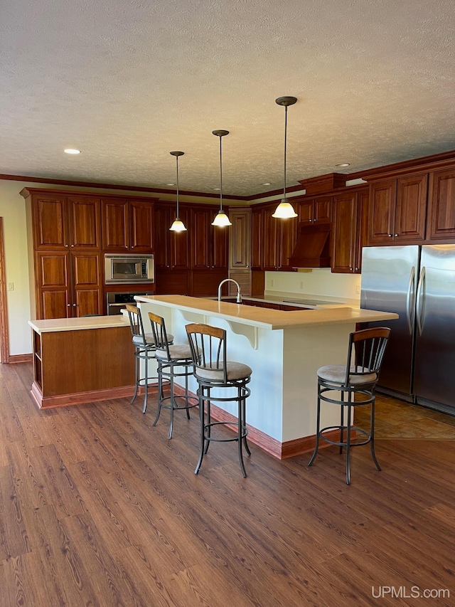 kitchen featuring appliances with stainless steel finishes, a spacious island, a kitchen breakfast bar, and dark hardwood / wood-style flooring