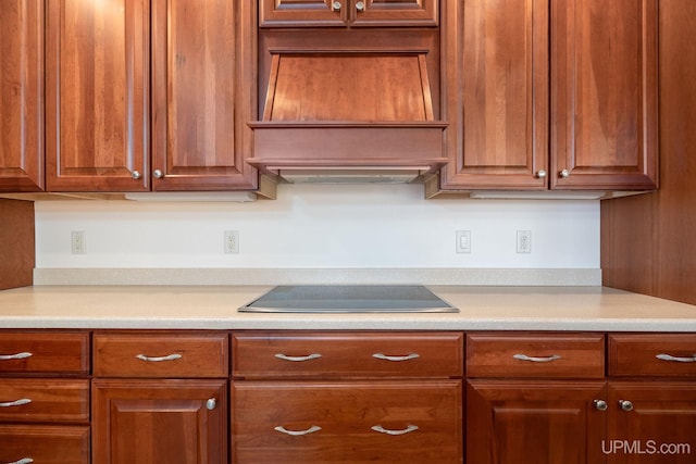 23 Chipman Dr, Ishpeming, MI 49849 - kitchen featuring cooktop, light countertops, custom range hood, and brown cabinetry