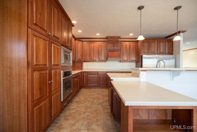 23 Chipman Dr, Ishpeming, MI 49849 - kitchen with stainless steel appliances, recessed lighting, light countertops, brown cabinets, and decorative light fixtures