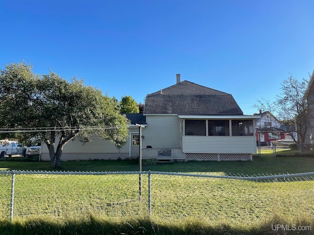 rear view of property featuring a lawn and a sunroom