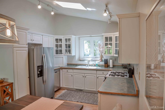 kitchen with stainless steel appliances, white cabinetry, sink, a skylight, and light wood-type flooring