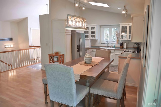 dining space with high vaulted ceiling, light hardwood / wood-style flooring, and sink