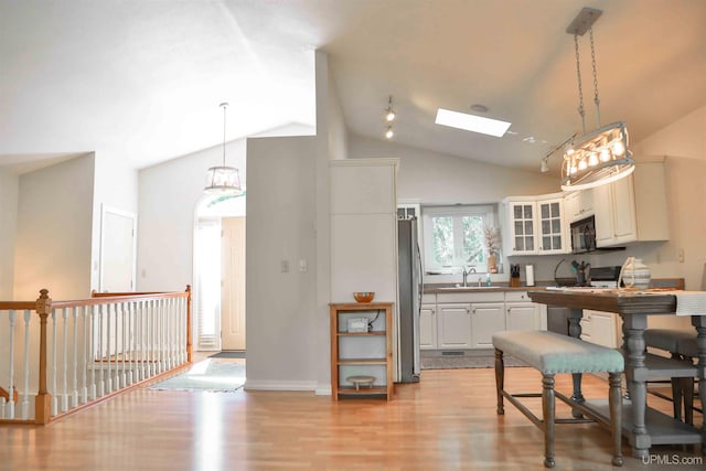 kitchen featuring white cabinets, stove, sink, and decorative light fixtures