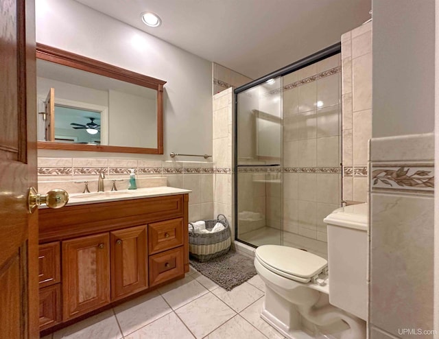 bathroom featuring walk in shower, ceiling fan, vanity, and tile walls