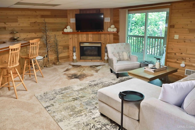 carpeted living room featuring a paneled ceiling and wooden walls