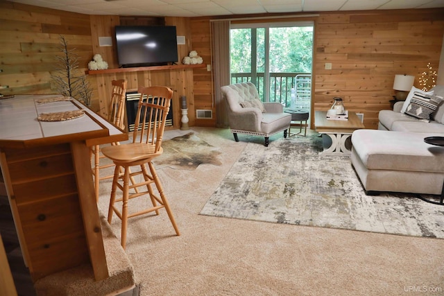 living room with a drop ceiling, wooden walls, and carpet