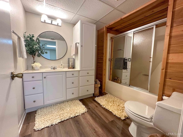 full bathroom with enclosed tub / shower combo, a paneled ceiling, vanity, hardwood / wood-style flooring, and toilet