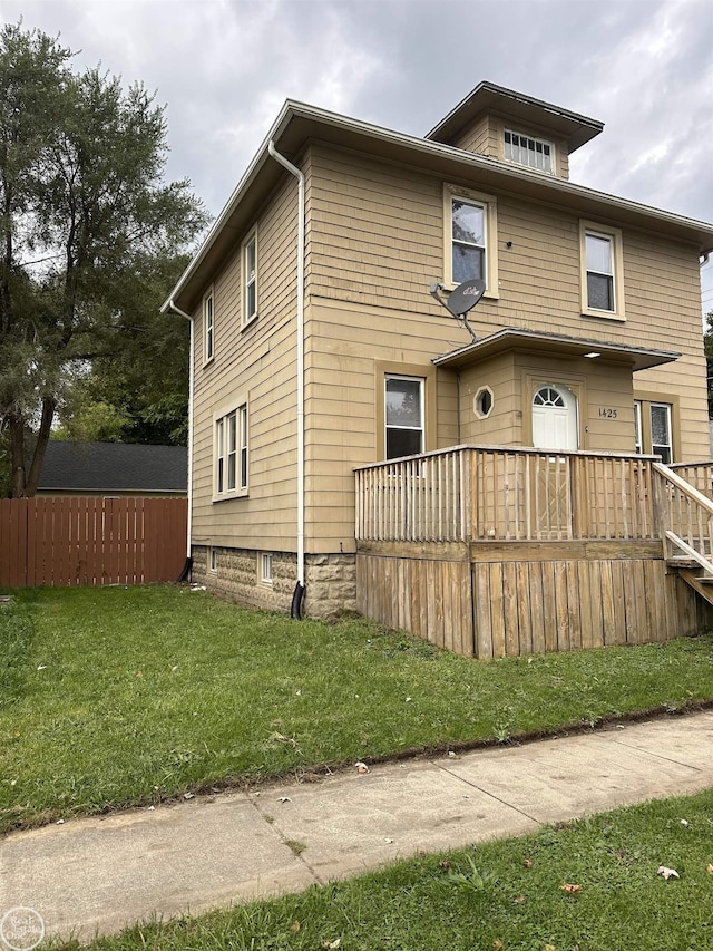 view of front facade with a wooden deck and a front yard