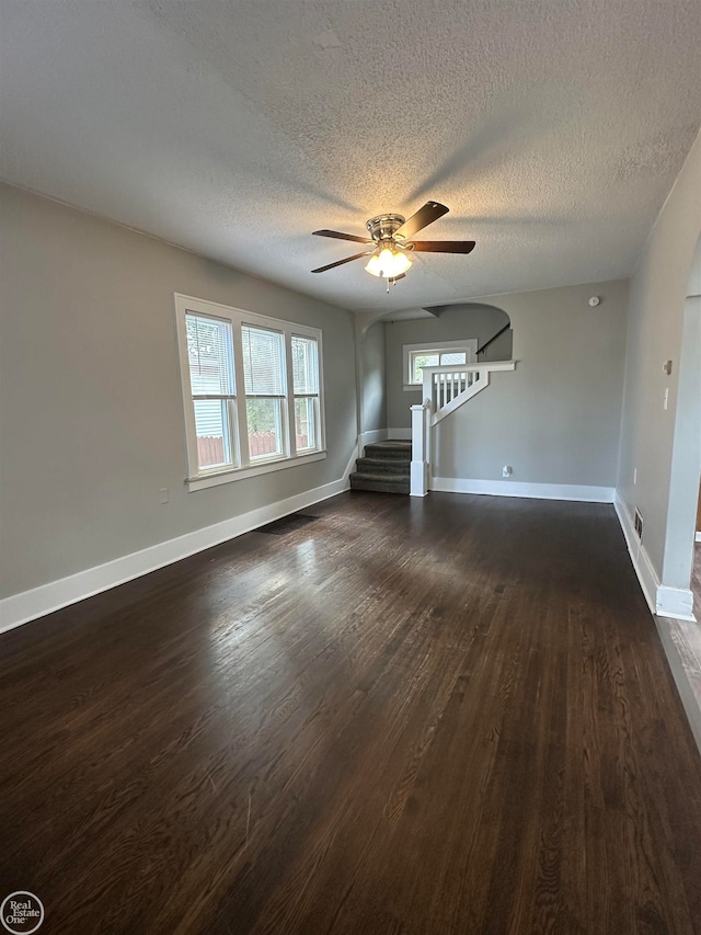 unfurnished living room with a textured ceiling, ceiling fan, and dark hardwood / wood-style floors