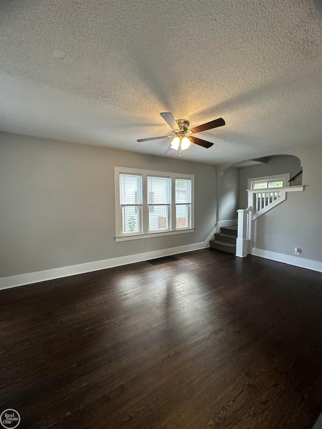 unfurnished living room featuring ceiling fan, dark wood-type flooring, and a textured ceiling