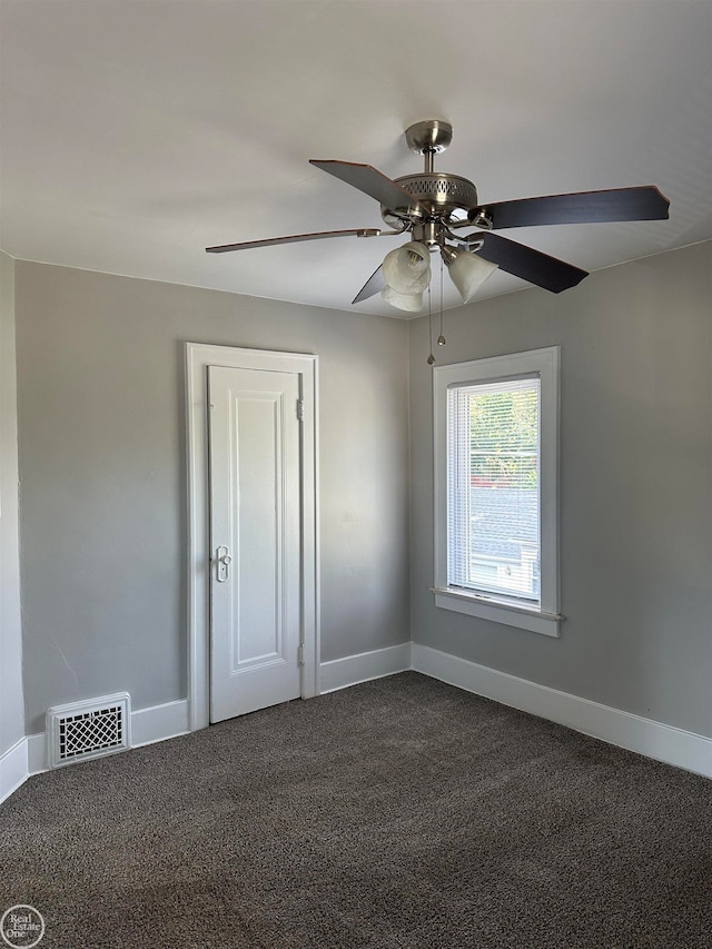 unfurnished room with ceiling fan and dark carpet