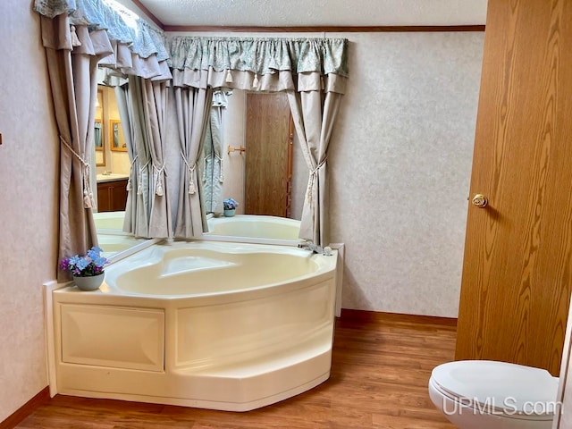 bathroom featuring a tub, wood-type flooring, a textured ceiling, crown molding, and toilet