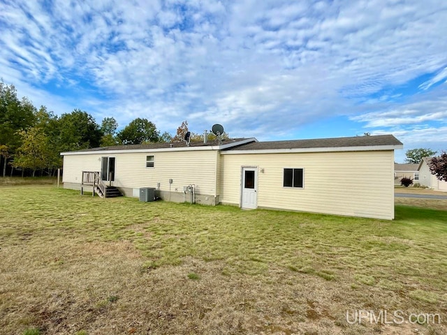 rear view of house featuring cooling unit and a yard