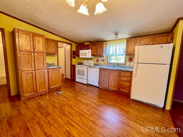 kitchen with a textured ceiling, hanging light fixtures, hardwood / wood-style floors, and white appliances