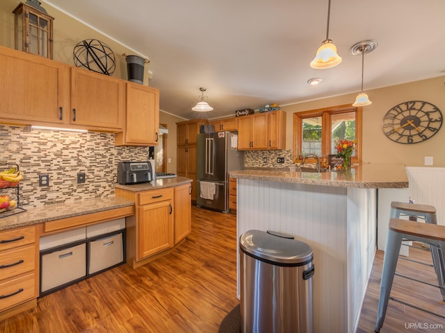 kitchen featuring light stone counters, light hardwood / wood-style floors, high quality fridge, backsplash, and decorative light fixtures