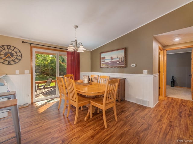 dining area with vaulted ceiling, an inviting chandelier, and hardwood / wood-style floors