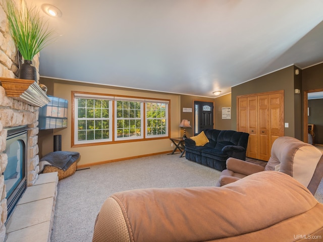 carpeted living room featuring a stone fireplace and vaulted ceiling