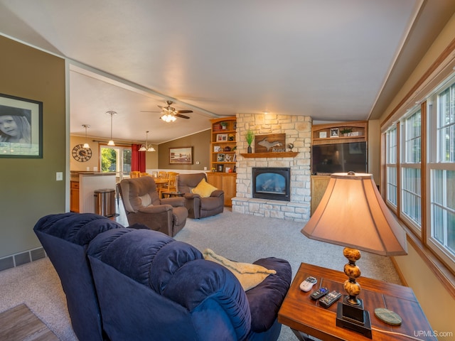 carpeted living room featuring lofted ceiling, ceiling fan, a fireplace, and built in features