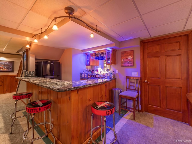 bar with light carpet, track lighting, black fridge, and a drop ceiling