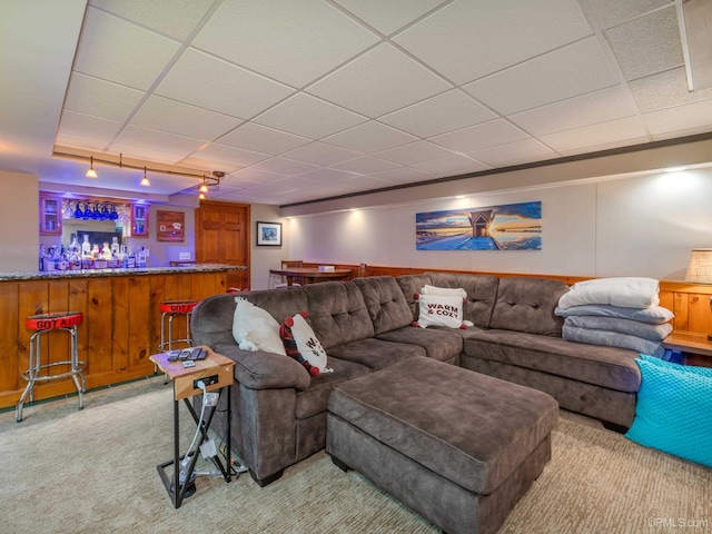 carpeted living room with a drop ceiling, bar area, and track lighting