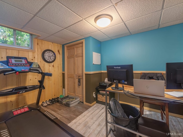 home office with wooden walls, hardwood / wood-style floors, and a paneled ceiling