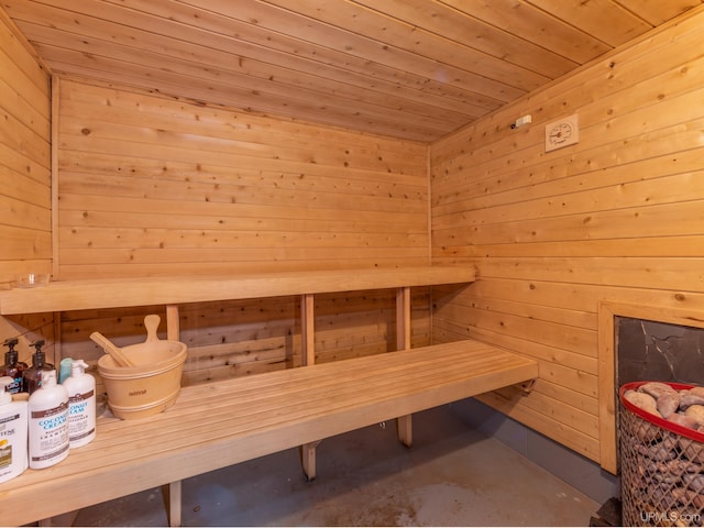 view of sauna featuring wood walls, concrete flooring, and wooden ceiling