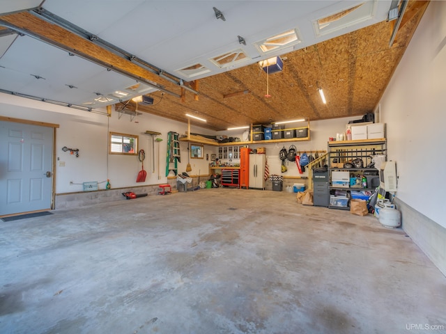 garage featuring a garage door opener, white fridge, and a workshop area