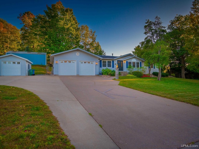 ranch-style house with a garage, a front lawn, and an outbuilding