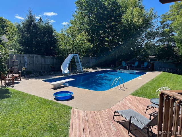 view of swimming pool with a lawn, a diving board, a water slide, and a patio area