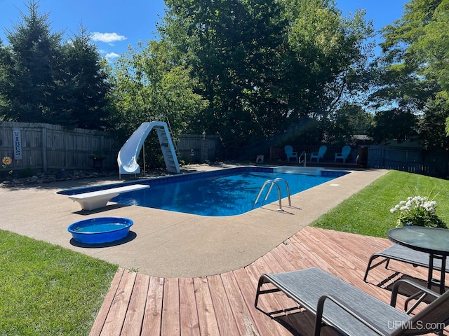 view of pool featuring a diving board, a yard, a water slide, and a patio area