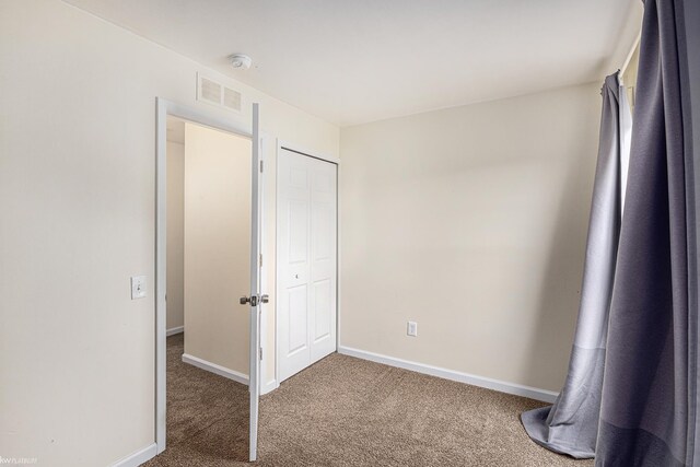 unfurnished bedroom featuring a closet, carpet flooring, visible vents, and baseboards