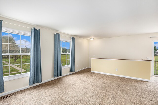 unfurnished room with carpet flooring, visible vents, and baseboards