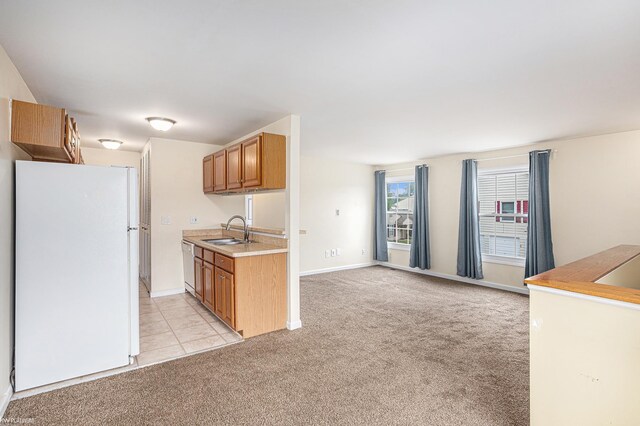kitchen featuring white appliances, light colored carpet, light countertops, a sink, and baseboards