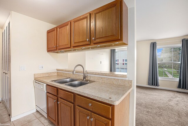 kitchen featuring a sink, brown cabinetry, light countertops, and white dishwasher