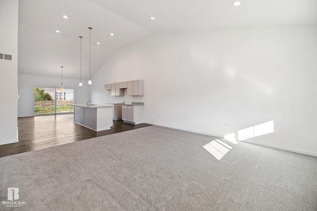 unfurnished living room featuring high vaulted ceiling and dark hardwood / wood-style flooring