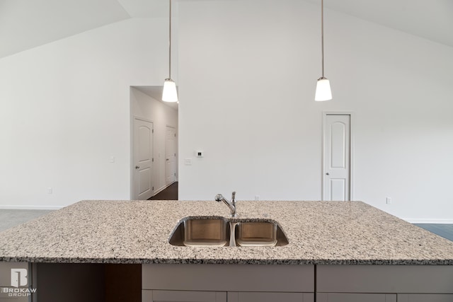 kitchen with pendant lighting, light stone countertops, lofted ceiling, and sink