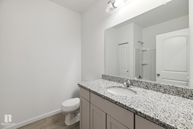 bathroom featuring walk in shower, wood-type flooring, toilet, and vanity