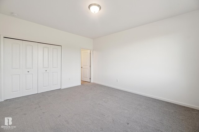 unfurnished bedroom with a closet and light colored carpet