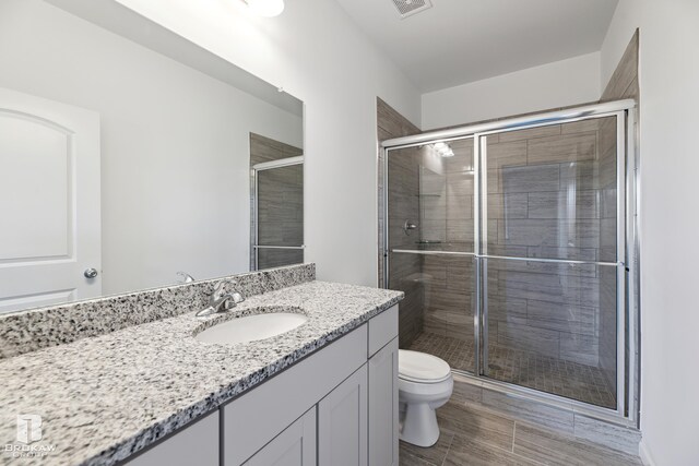 bathroom with vanity, toilet, and a shower with door